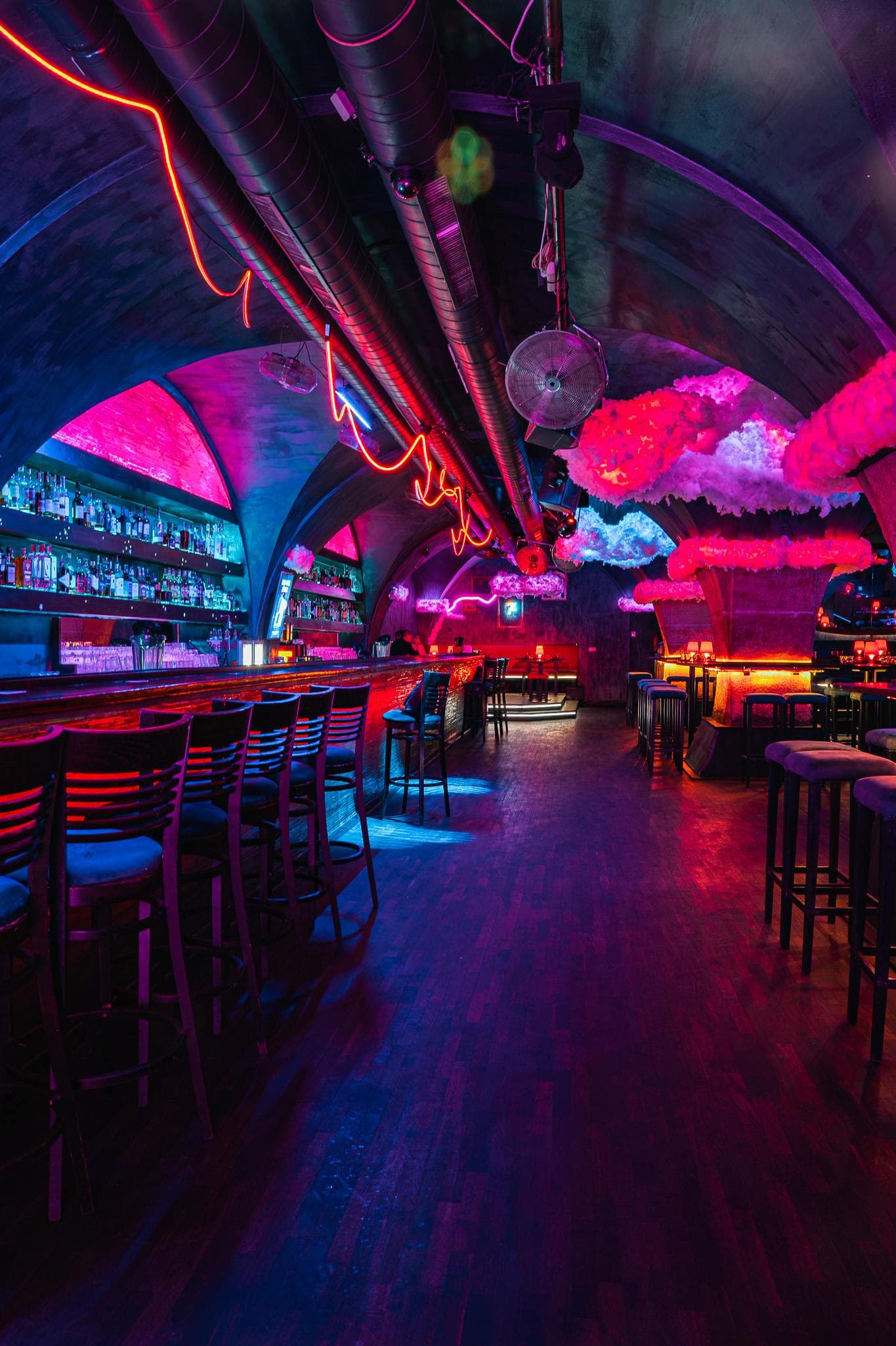 Tables along the wall and the dance floor in pink neon